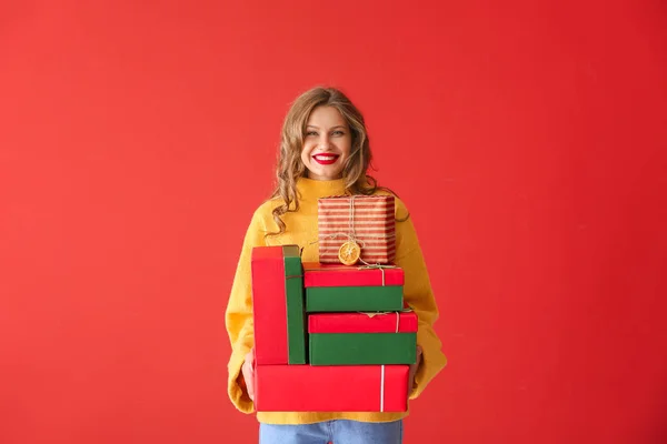 Joyeux jeune femme avec des cadeaux de Noël sur fond de couleur — Photo