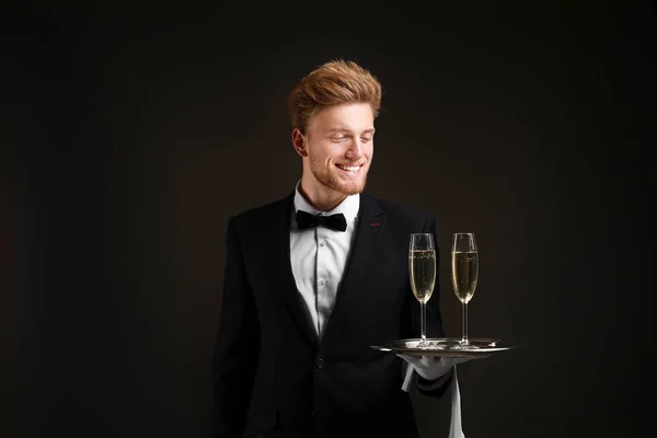 Handsome waiter with champagne on dark background — Stock Photo, Image