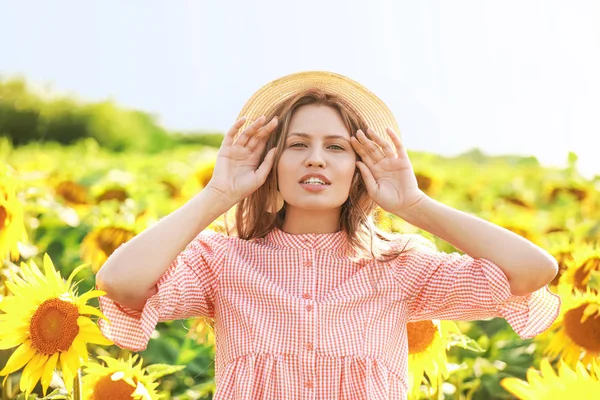 Beautiful young woman in sunflower field on summer day — Stock Photo, Image