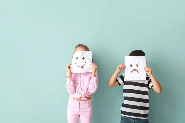 Little children hiding faces behind drawn emoticons on color background — Stock Photo, Image