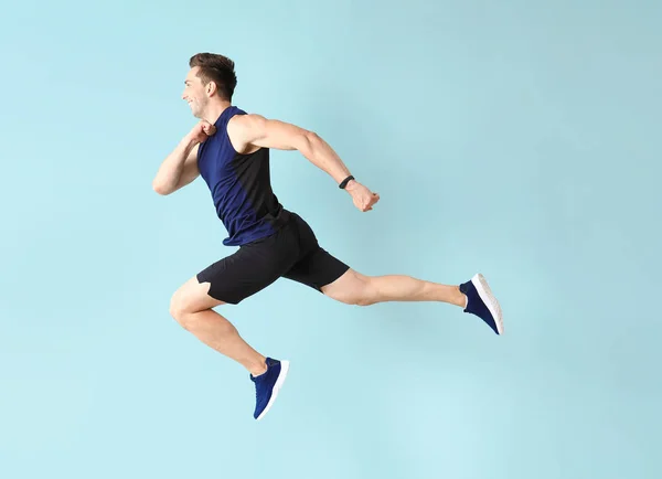 Running sporty man on color background — Stock Photo, Image