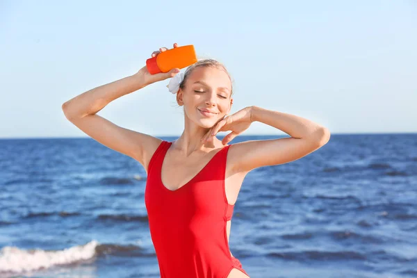 Hermosa mujer joven con crema de protección solar en la playa de mar — Foto de Stock