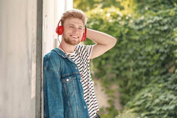 Knappe jongeman luisteren aan muziek in openlucht — Stockfoto