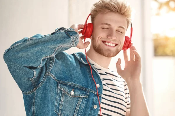 Knappe jongeman luisteren aan muziek in openlucht — Stockfoto