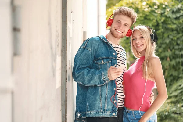 Young couple listening to music outdoors