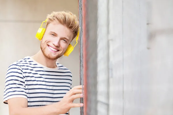 Knappe jongeman luisteren aan muziek in openlucht — Stockfoto