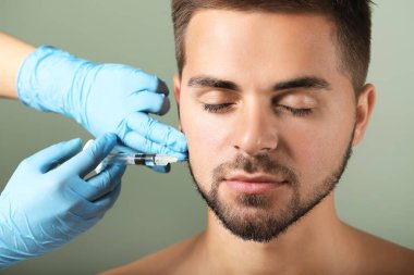 Yakışıklı adam renk arka plan üzerinde dolgu enjeksiyonu alan