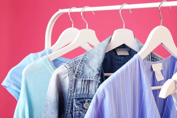 Rack with hanging clothes on color background, closeup — Stock Photo, Image