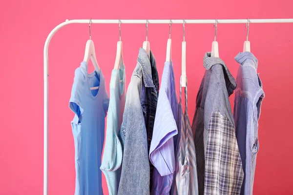 Rack with hanging clothes on color background — Stock Photo, Image