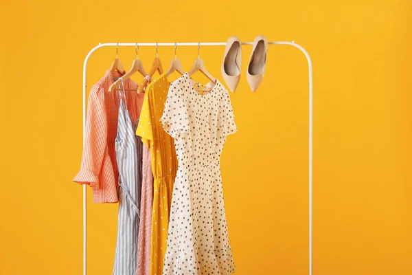 Rack with hanging clothes on color background — Stock Photo, Image