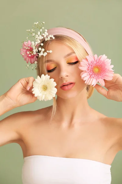 Vacker ung kvinna med blommor på färg bakgrund — Stockfoto