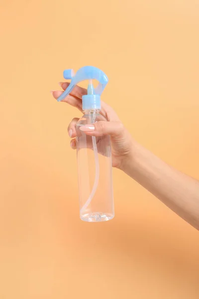 色の背景に空気清浄剤のボトルを持つ女性の手 — ストック写真