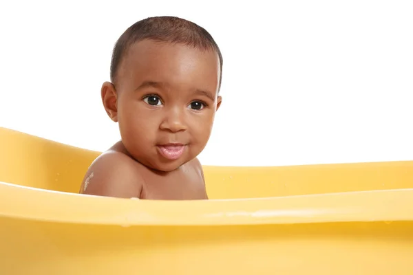 Little African-American baby washing in bathtub against white background — Stock Photo, Image