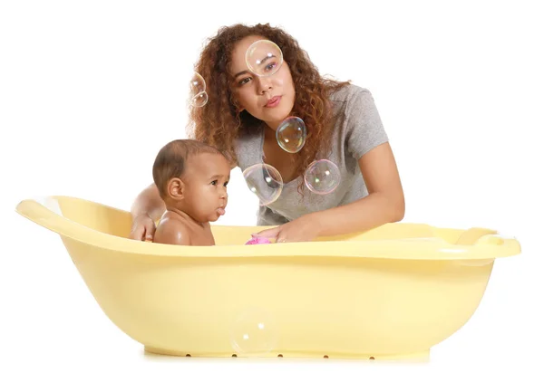 Ibu muda Afrika-Amerika mencuci bayinya di bak mandi dengan latar belakang putih — Stok Foto