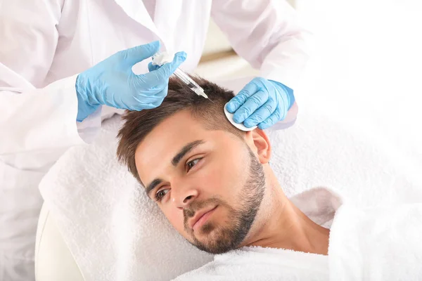 Человек с проблемой выпадения волос получает инъекцию в клинике — стоковое фото