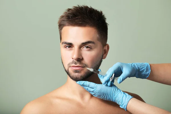 Bonito homem recebendo injeção de enchimento no fundo da cor — Fotografia de Stock