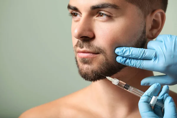 Handsome man receiving filler injection on color background — Stock Photo, Image