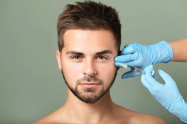 Knappe man ontvangen filler injectie op kleur achtergrond — Stockfoto