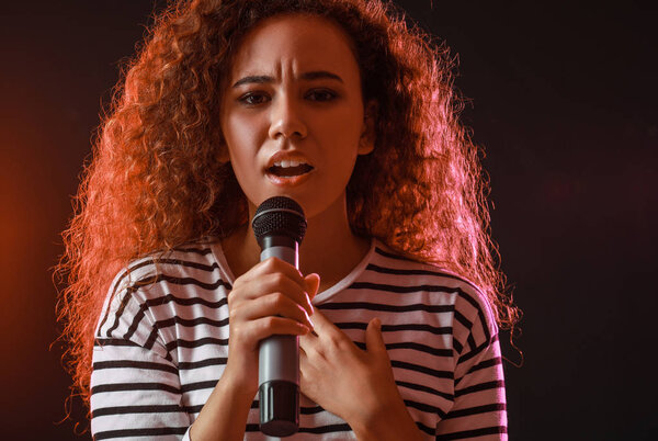 Красивая афро-американская певица с микрофоном на сцене
