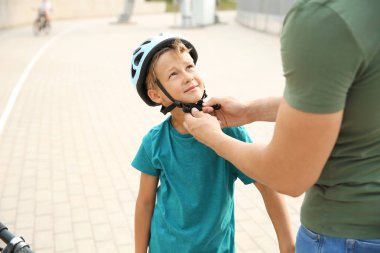 Baba dışarıda bisikletsürmeden önce kask koymak için oğlu yardım