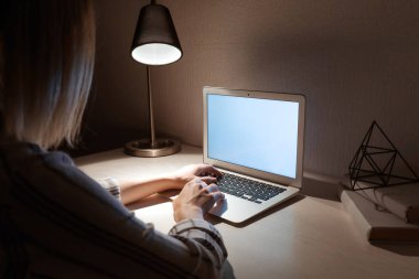Akşam masada dizüstü bilgisayar üzerinde çalışan kadın