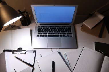 Akşamları dizüstü bilgisayar ve kırtasiye ile modern işyeri