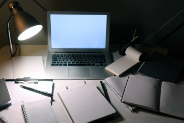 Akşamları dizüstü bilgisayar ve kırtasiye ile modern işyeri