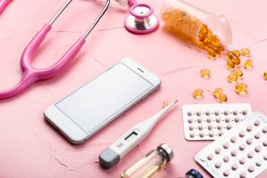 Renk arka planda stetoskop ve haplar ile modern cep telefonu