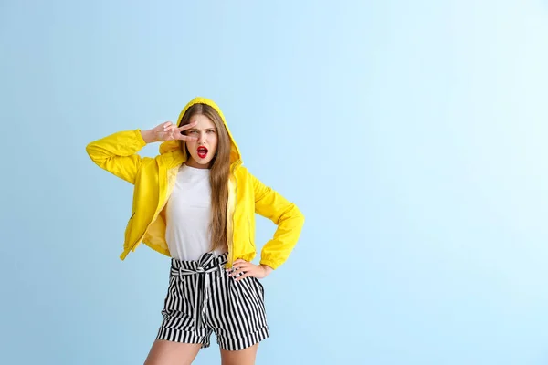 Lustige junge Frau zeigt Siegesgeste auf farbigem Hintergrund — Stockfoto