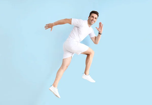 Running sporty man on color background — Stock Photo, Image