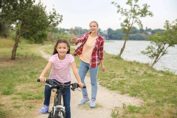 Mother teaching her daughter to ride bicycle outdoors — Stock Photo, Image