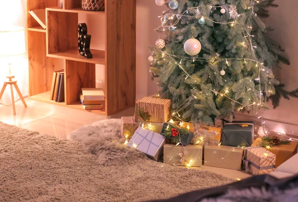 Hermosos regalos de Navidad bajo el abeto en el suelo en la habitación —  Fotos de Stock