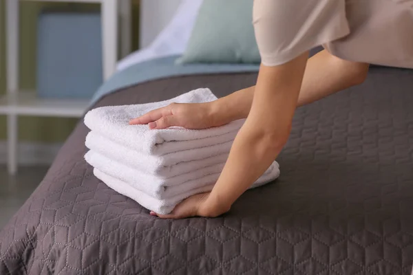 Female housekeeper putting clean towels on bed — Stock Photo, Image