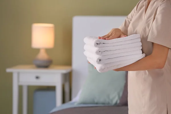 Female housekeeper with clean towels in bedroom — Stock Photo, Image