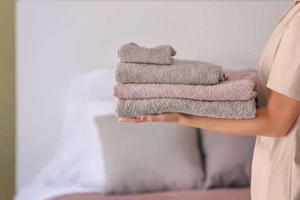 Female housekeeper with clean towels in bedroom — Stock Photo, Image