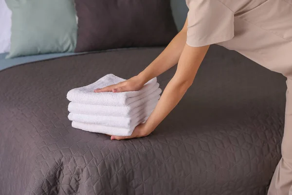 Female housekeeper putting clean towels on bed — Stock Photo, Image