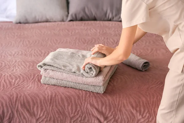 Female housekeeper putting clean towels on bed — Stock Photo, Image
