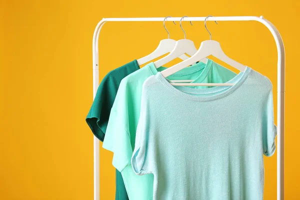Rack with hanging clothes on color background — Stock Photo, Image
