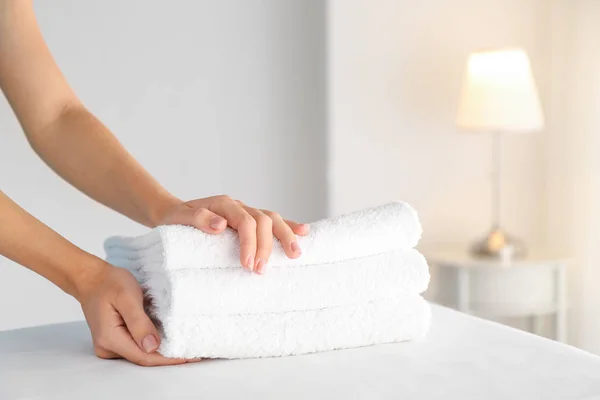 Female housekeeper putting clean towels on table — Stock Photo, Image