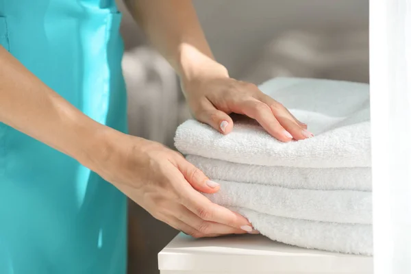 Female housekeeper putting clean towels on table — Stock Photo, Image