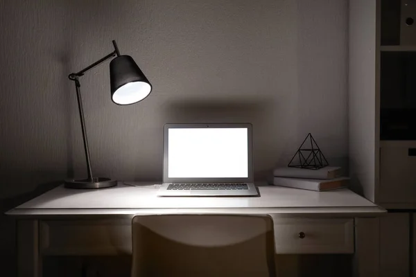 Modern workplace with laptop in evening — Stock Photo, Image