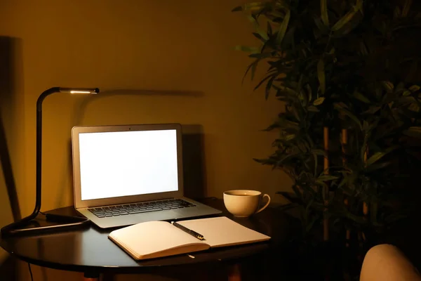 Modern workplace with laptop in evening — Stock Photo, Image