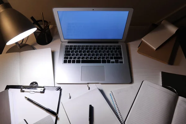 Modern workplace with laptop and stationery in evening — Stock Photo, Image