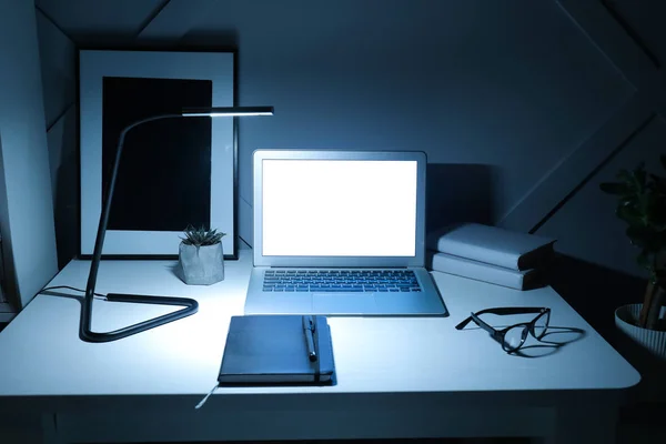 Современное рабочее место с ноутбуком вечером — стоковое фото