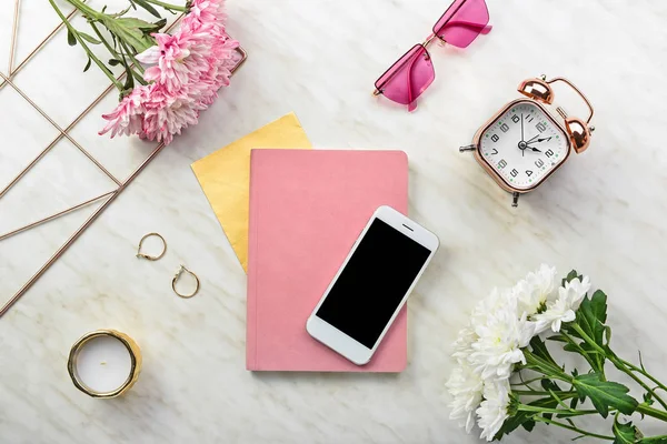 Modern mobile phone with notebook and female accessories on light background — Stock Photo, Image