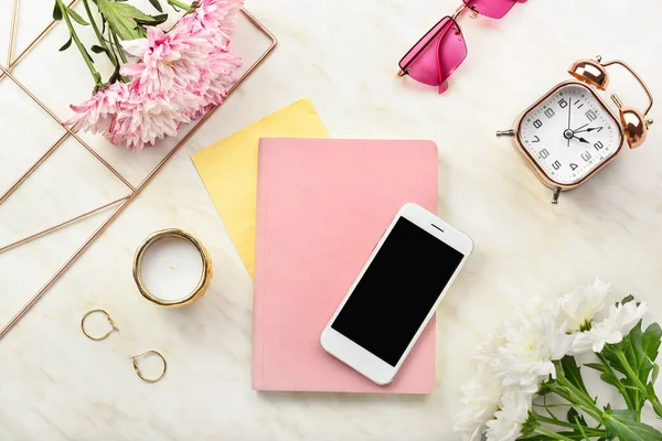 Modern mobile phone with notebook and female accessories on light background — Stock Photo, Image