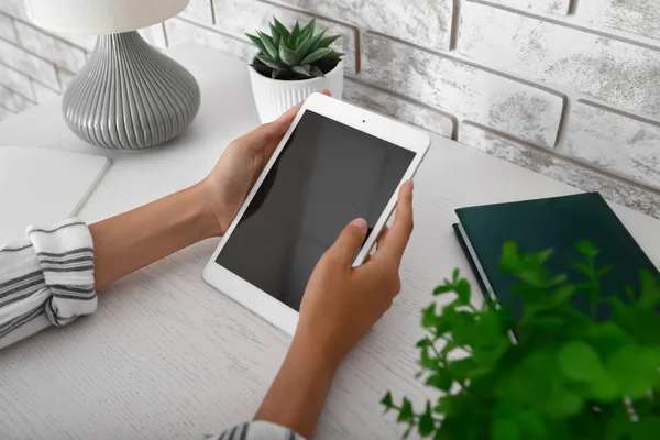 Vrouw met moderne tablet computer zittend aan tafel, close-up — Stockfoto