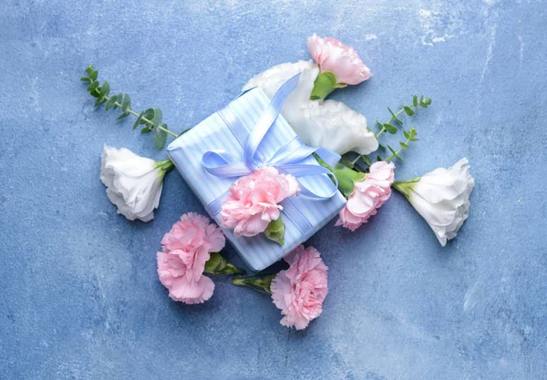 Mooie bloemen en cadeau op kleur achtergrond — Stockfoto