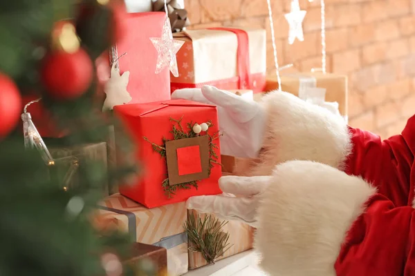 Jultomten sätta presentförpackning på mantelpiece, närbild Stockbild