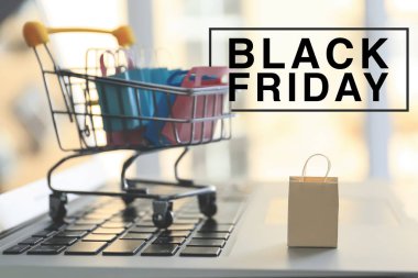 Dizüstü bilgisayarda alışveriş sepeti ile küçük kağıt torbalar. Black Friday satışı